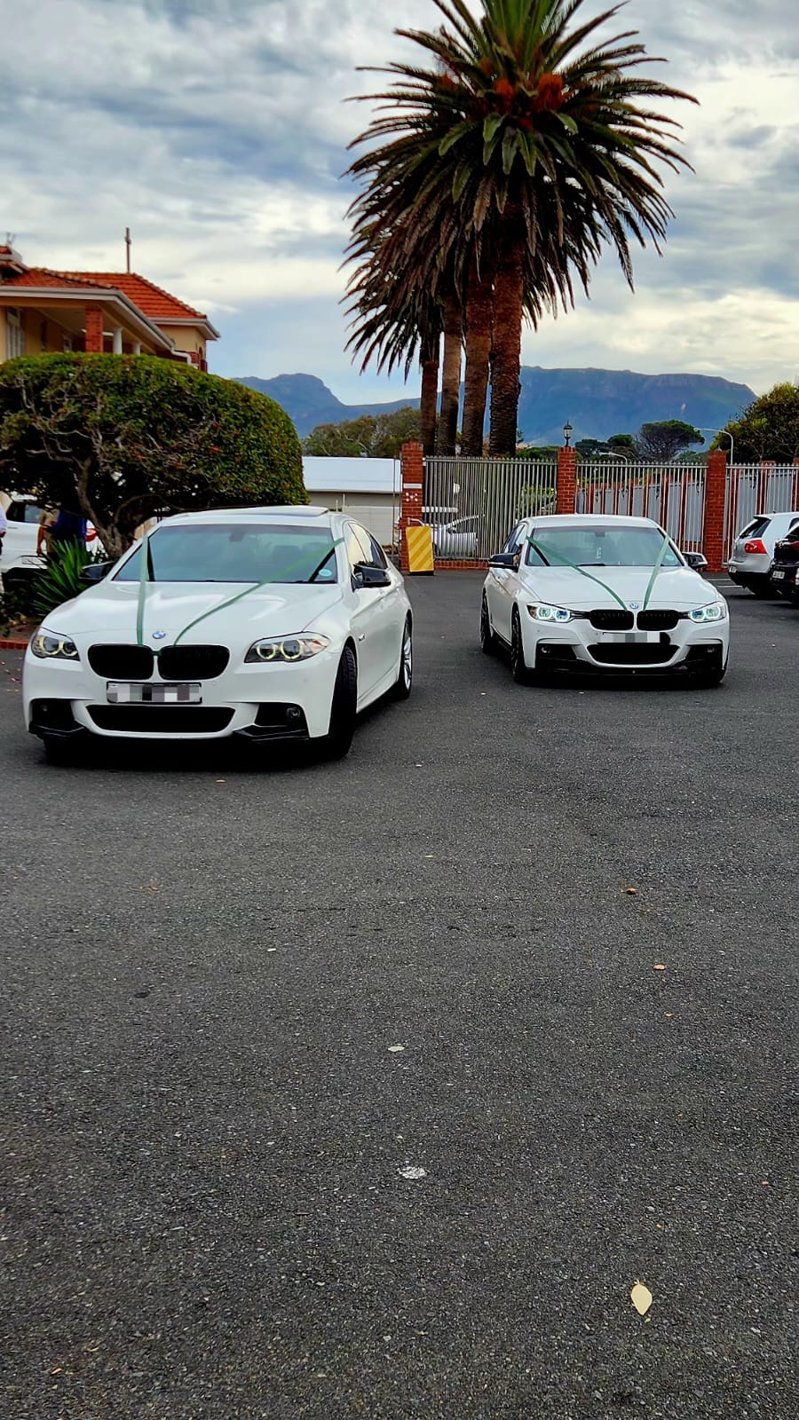 Two white BMW wedding cars with a Cape Town mountain backdrop