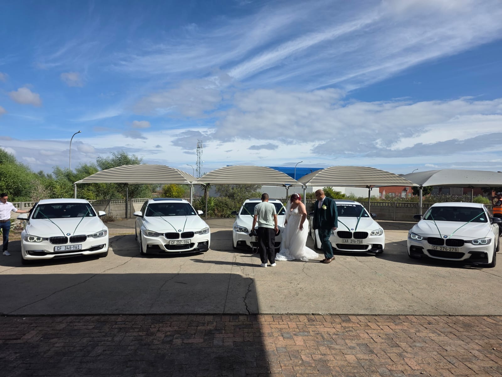 Five white BMW wedding cars lined up with the bride and groom at a Cape Town venue
