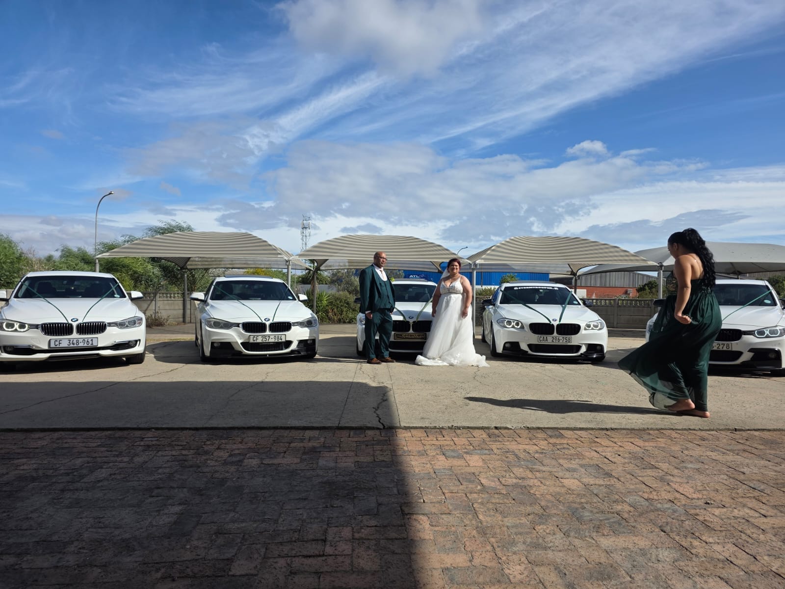 Bride and groom standing between white BMW wedding cars in Cape Town